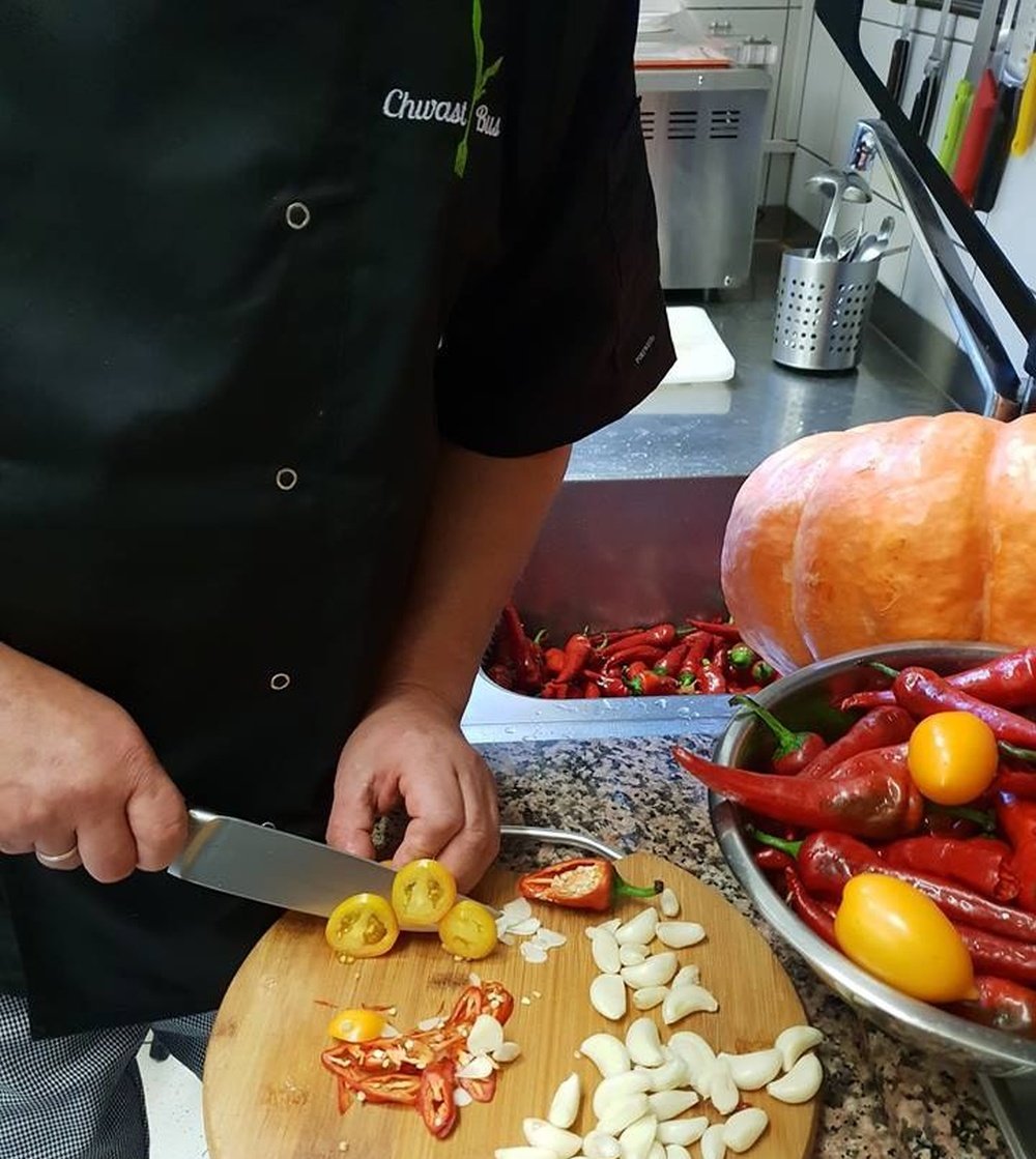 Zdjęcie przedstawia szefa kuchni krojącego ostre papryczki