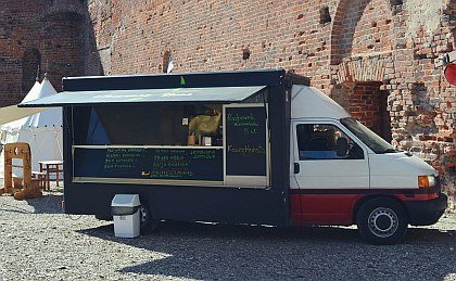Zdjęcie przedstawia food tracka na tle zamku Dybowskiego