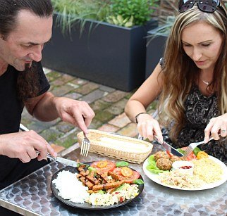 Zdjęcie przedstawia kobietę i mężczyznę jedzących posiłek przy stoliku w ogródku restauracji Chwast Prast