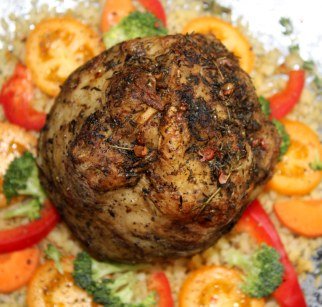 Zdjęcie przedstawia udekorowany warzywami talerz, na nim upieczony z ziołami seler