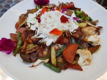 Zdjęcie przedstawia smażone krótko warzywa z woka podawane z makaronem ryżowym