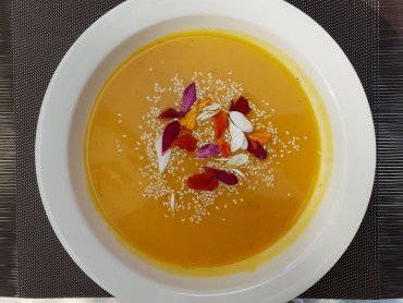 Zdjęcie przedstawia talerz z kremem z dyni z liściem bergamotki