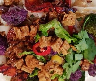 Na zdjęciu talerz, na nim potrawa Yuba z warzywami podana z warzywami i makaronem ryżowym