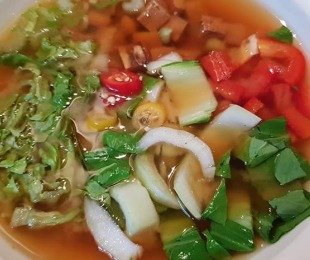 Zdjęcie przedstawia talerz zupy Miso z kapustą pak choi, sałatą rzymską, groszkiew cukrowym, tofu i papryką