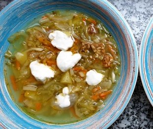 Zdjęcie przedstawia talerz zupy Ogórkowej z tempehem i kwaśną śmietaną