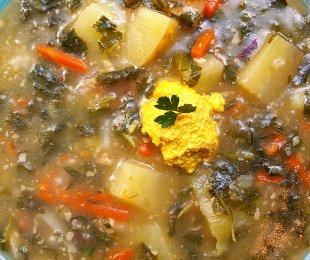 Zdjęcie przedstawia talerz zielonego barszczu pokrzywowo podagrycznikowego z vegańskim żółtkiem