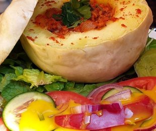 Na zdjęciu talerz, na nim patison zapieczony z pomidorowym farszem sojowo warzywnym podany z warzywami