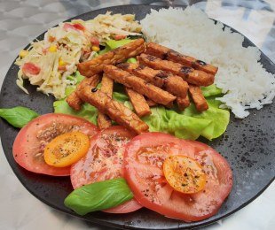 Na zdjęciu talerz, na nim smażone słupki tempehu, podane z ryżem i warzywami