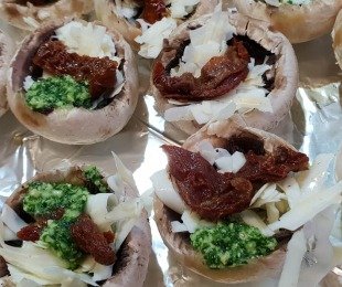 Na zdjęciu talerz, na nim Pieczarki a'la Gucia faszerowane pesto, vegańską mozzarellą i suszonymi pomidorami