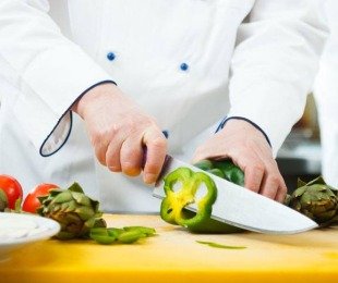 Na zdjęciu kucharz kroi paprykę i karczochy