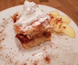 Na zdjęciu talerzyk z porcją szarlotki z bitą śmietaną